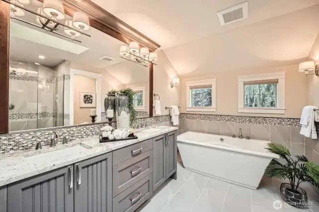 Spa-like primary bath features a spacious curbless shower, freestanding soaking tub, extra-long double vanity, and designer lighting and mirrors for a luxurious retreat.