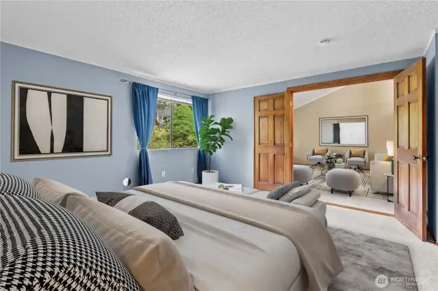 Large primary bedroom with french doors opening into living room- virtually staged