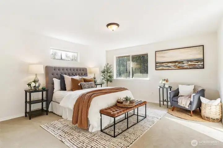 Spacious primary bedroom with plush carpet, calming tones, and room for seating.