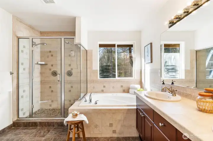 Spa-inspired primary bathroom with soaking tub, glass-enclosed shower, and dual-sink vanity.