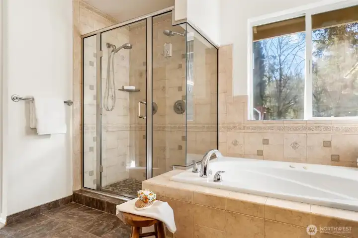 Relaxing soaking tub paired with a tiled walk-in shower and large window.