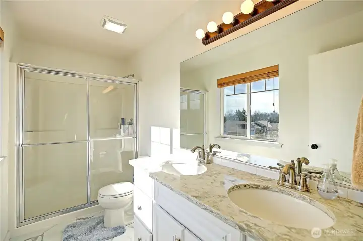 The attached ¾ bath features a spacious walk-in shower, dual-sink vanity, and bright natural light. Crisp finishes and a functional layout create a refreshing, comfortable space to start and end your day.