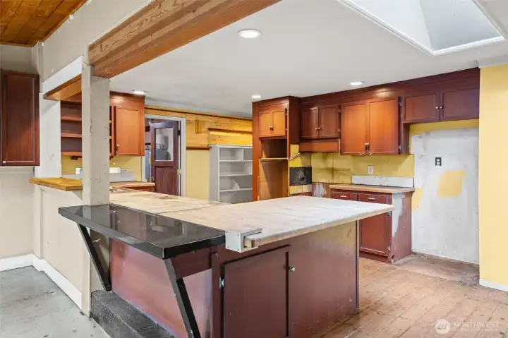 Open living and kitchen area with exposed beams and skylights creates a bright, airy feel. Ideal layout for reconfiguring into a contemporary great room.