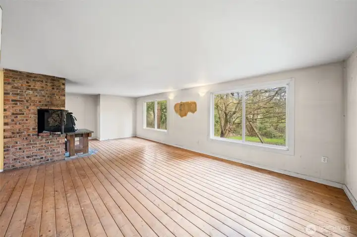 Living room features updated vinyl windows bringing in natural light and showcase peaceful, wooded views. Generous space ready for renovation and reimagining into a modern living area.