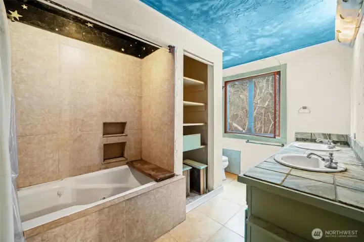 Generous en suite bath featuring soaking tub, dual sinks, and built-in storage. Ready for renovation into a spa-inspired primary bathroom.