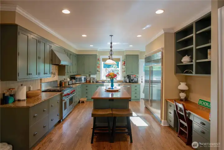 The chef's kitchen stuns with granite countertops, a 72" side-by-side refrigerator/freezer, propane cooktop with electric oven, and a pot filler above the stove.