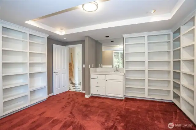 Spacious lower-level library or craft room, thoughtfully designed with built-in shelving and a convenient cabinet with a sink—easily adaptable to suit your unique needs.