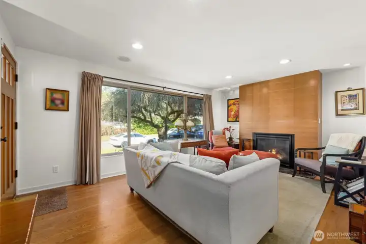 The living room features a wall of windows: picture window and sidelights with sliding hardware and screens for fresh air.