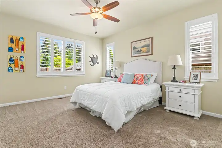 Primary suite with custom plantation shades and ceiling fan.