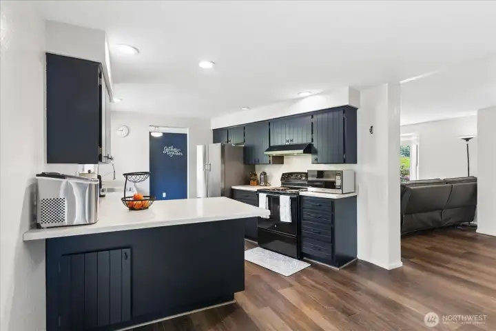 Chef’s kitchen featuring refreshed cabinetry in a modern dark finish, complemented by ample counter space and a peninsula breakfast bar, perfect for meal prep and casual dining.