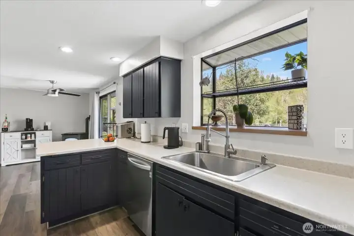 The functional kitchen layout includes a deep stainless steel sink and a large garden window, providing plenty of natural light and peaceful views of the beautiful surrounding greenery while you work.
