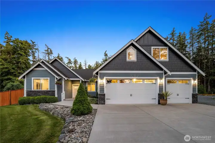Elegant curb appeal meets modern craftsmanship, featuring striking architectural details, a spacious three-car garage & serene wooded setting.