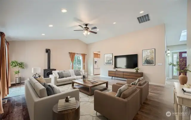 Spacious living area with vaulted ceilings and freestanding propane fireplace. (virtually staged)