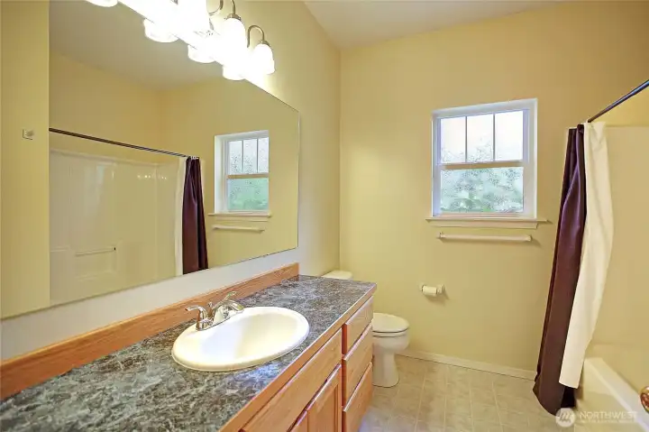 Light & bright guest bathroom offers a tub and plenty of counterspace.