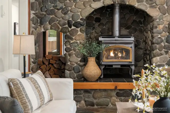 River rock fireplace with wood storage. Efficient wood-burning stove.