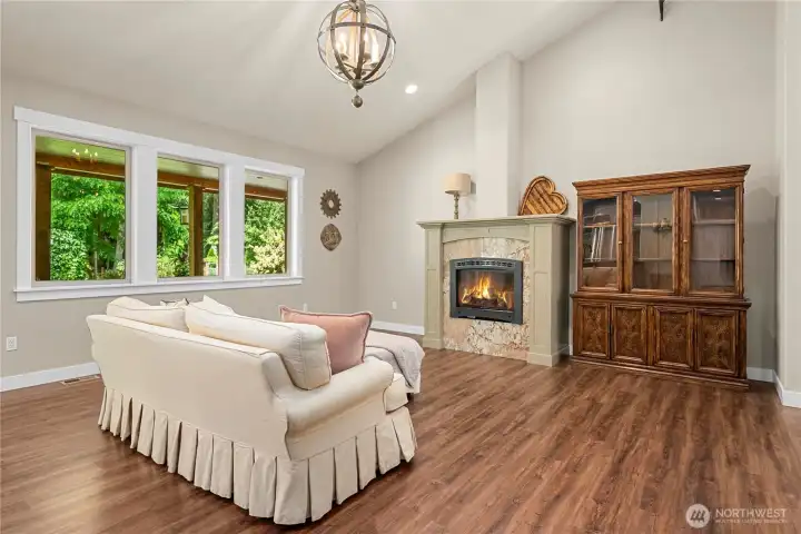 Vaulted living room with windows showing off the backyard
