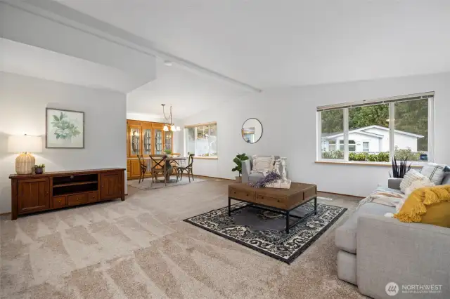 A spacious living room with soaring vaulted ceilings and abundant natural light creates an airy, open, and inviting atmosphere. Fresh new interior paint and flooring throughout home.