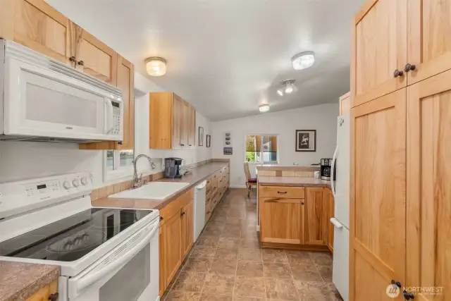 Custom kitchen with rich hickory cabinets with pantry storage and oversized drawers—designed for both beauty and function.