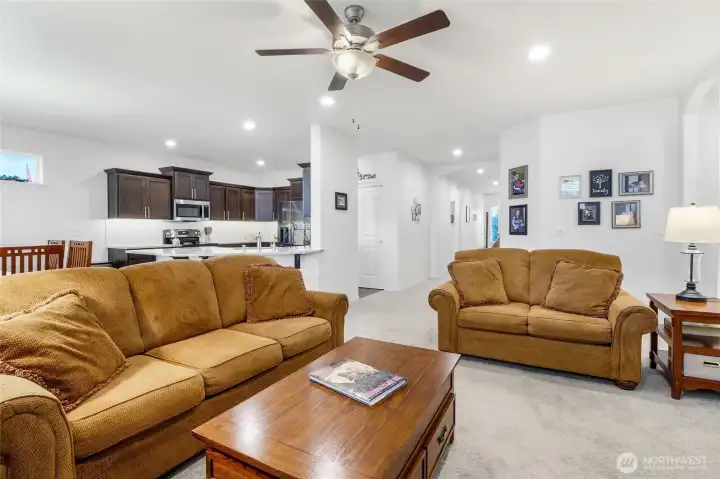 You get a feeling of space and tidiness as you view this wide photo of living room, kitchen, and hallway to the front door.