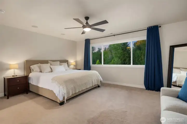 The primary suite features luxuriously plush carpet and large windows overlooking parklike views.