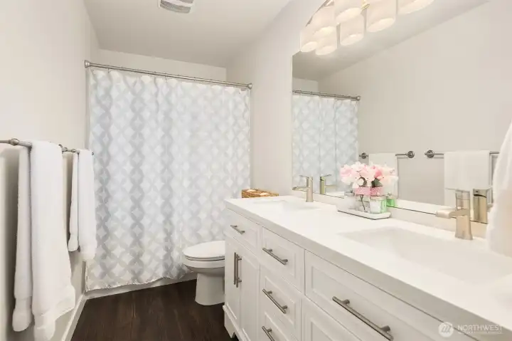 The main bathroom on the upper level is light and airy with updated cabinetry, and bright, modern lighting.