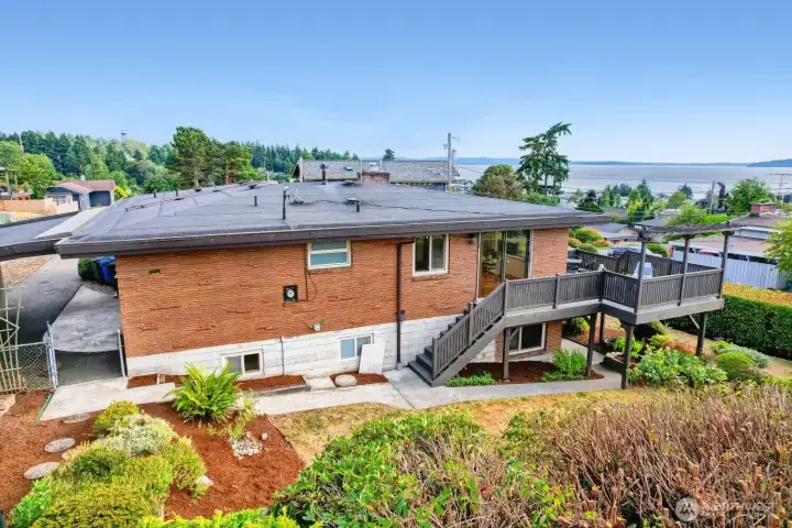 Rear of Home with Puget Sound Views The rear of this mid-century home showcases clean architectural lines, a brick exterior, and an expansive deck designed for outdoor living. Large windows frame scenic views of Puget Sound and surrounding greenery, while the tiered landscaping adds depth and character to the property. Thoughtful updates and well-maintained grounds create a seamless blend of indoor comfort and outdoor enjoyment—perfect for entertaining or relaxing in the Northwest sunshine. Rear of Home with Puget Sound Views The rear of this mid-century home showcases clean architectural lines, a brick exterior, and an expansive deck designed for outdoor living. Large windows frame scenic views of Puget Sound and surrounding greenery, while the tiered landscaping adds depth and character to the property. Thoughtful updates and well-maintained grounds create a seamless blend of indoor comfort and outdoor enjoyment—perfect for entertaining or relaxing in the Northwest sunshine.