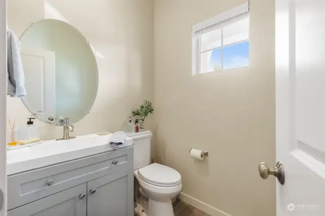 This charming powder room has been completely upgraded, featuring a custom, non-standard vanity that adds a touch of luxury and uniqueness to the space. The sleek design is complemented by soft neutral tones and contemporary finishes. The round mirror adds a stylish touch, while natural light from the window creates a bright and airy feel. Perfectly sized for guests, this newly upgraded bathroom combines practicality with elegant simplicity, making it a standout feature in this thoughtfully designed home.