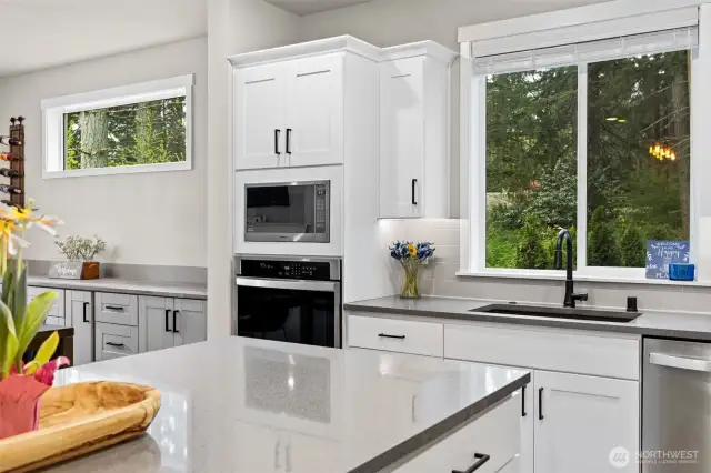 Kitchen sink overlooks green trees next.  Modern black faucet and black undermount sink.