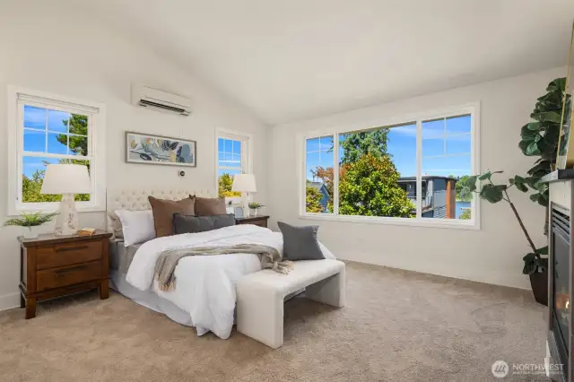 Luxurious primary bedroom features a vaulted ceiling, gas fireplace and partial lake views!