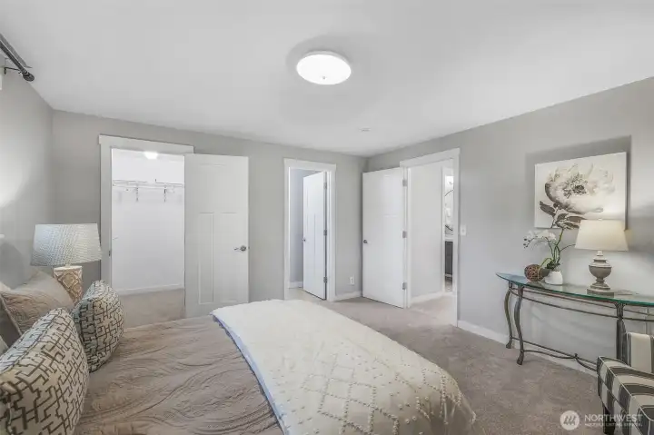 Another view of the primary suite highlights its walk-in closet and direct access to a private bath. The generous layout offers space to unwind at the end of the day.