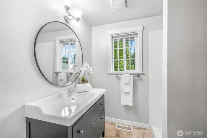The private three-quarter bath in the primary suite features updated finishes, a modern vanity, and a window for natural light. A comfortable space designed for convenience.