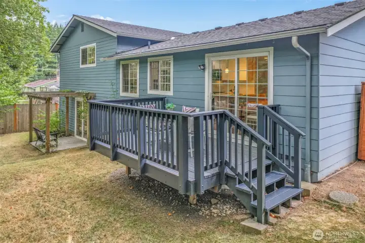The backyard offers a lawn with multiple spaces for relaxation or play. The deck and patio areas create an extension of the home’s living space into the outdoors.