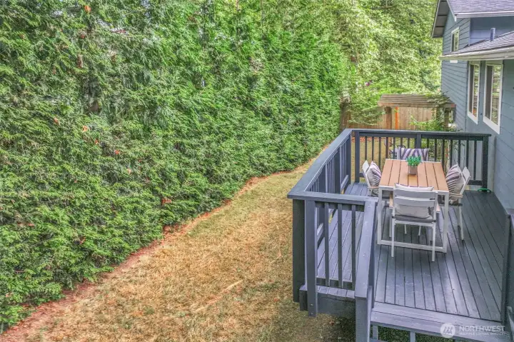 The back deck overlooks a fully fenced yard bordered by tall evergreens for privacy. It’s an ideal space for entertaining, dining outdoors, or simply enjoying the peaceful setting.
