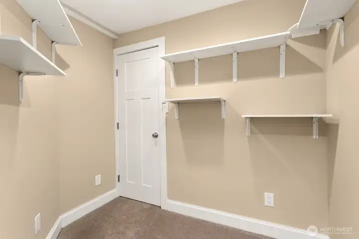 Tidy and functional storage room with built-in shelving. This space is perfect for organizing seasonal items, hobbies, or keeping household essentials easily accessible. More storage located in the closet shown, which leads to under-stair storage.