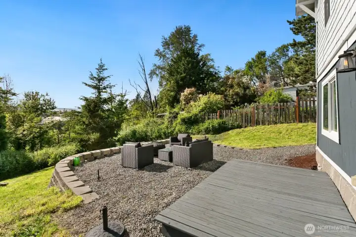 Relax or entertain in the terraced backyard retreat, featuring a sunny gravel patio, raised deck, and lush natural privacy with views of SODO, Puget Sound water view, West Seattle, and the Olympic Mountains.