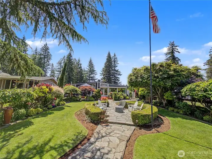 Reminiscent of a private estate garden, this stunning outdoor living space features custom stonework, manicured hedges, and breathtaking landscaping at every turn. A serene retreat designed for entertaining, relaxing, and enjoying the beauty of the outdoors.