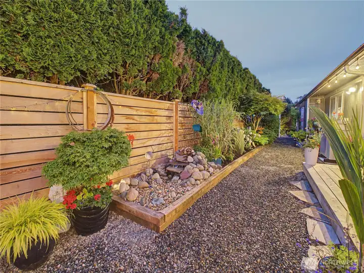 A peaceful garden pathway winds through thoughtfully designed landscaping, creating a private retreat just outside your door. Mature hedging, accent lighting, and a tranquil water feature add to the property's resort-like atmosphere.