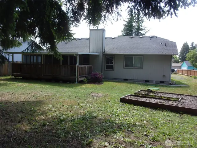 Picture of the back of the home from under the fir trees.