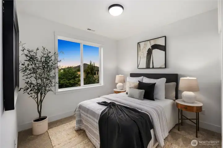 Main Floor Bedroom: Bright bedroom with oversized window showcases territorial views. Neutral palette and plush carpet create a welcoming retreat for family or guests.    Photos are from a previous Glacier model home at Foxmoore and are for visualization purposes only - colors, selections, and included feature can and will vary.