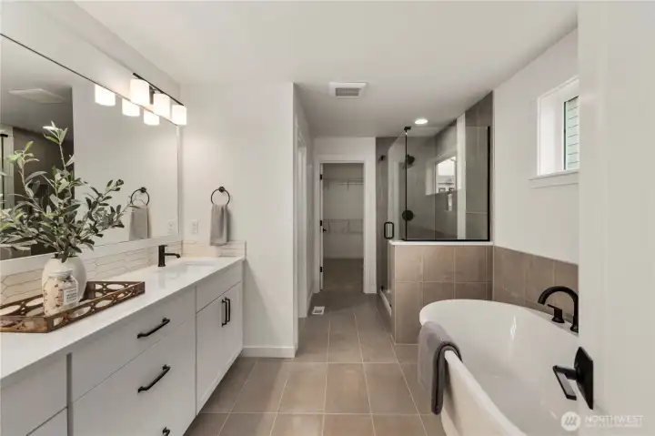 Primary Bath: Luxurious spa-inspired bath features dual vanities, quartz counters, soaking tub, and a glass-enclosed shower. Elegant finishes pair with abundant natural light, creating a rejuvenating retreat.    Photos are from a previous Glacier model home at Foxmoore and are for visualization purposes only - colors, selections, and included feature can and will vary.