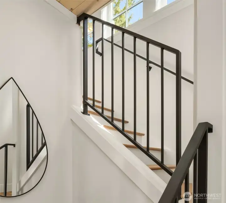Custom metal handrails lead up solid wood stairs to the upper level.