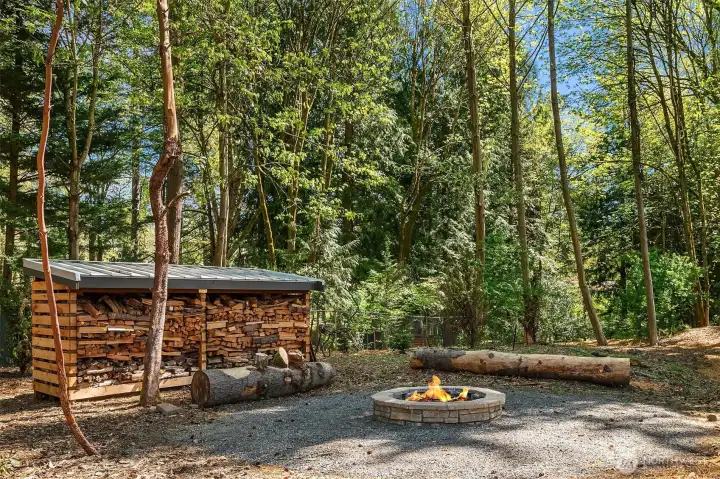 A community fire pit stands ready with plenty of firewood.