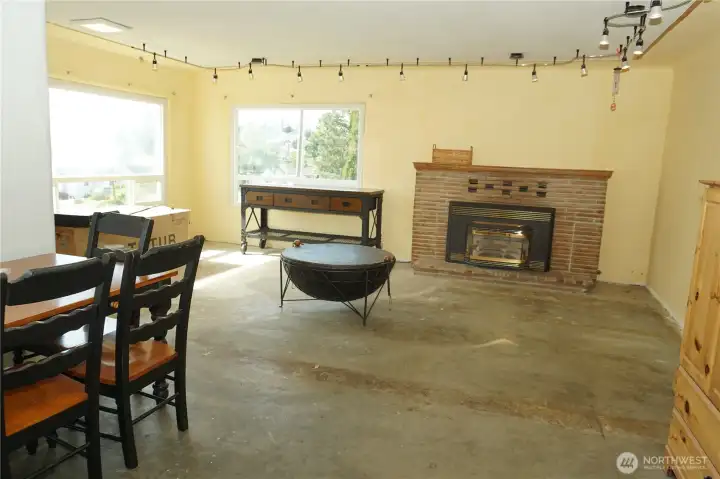 Large living room with a gas fireplace insert, concrete slab floors, large windows to see the views to the west and north. The window on the west has lost its seal and is failed. Sold as is.