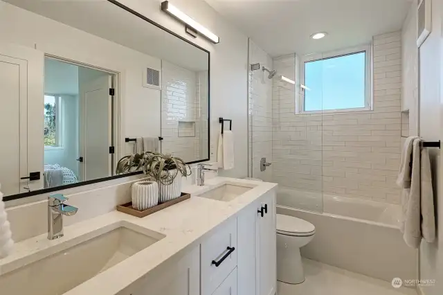 Secondary bathroom with soaking tub,   designer tile from Statements, and frameless glass enclosure.