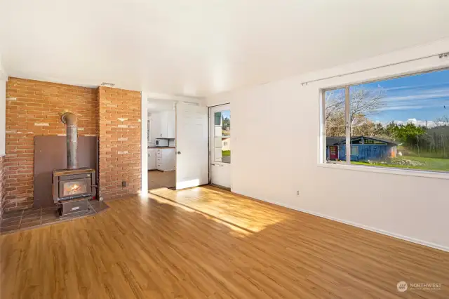 The sunny living room with a cozy wood stove and plenty of natural light from the windows.
