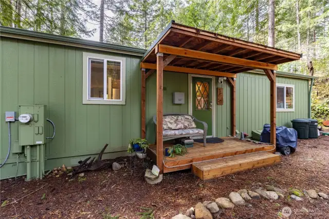 This cozy side entry welcomes you with a charming covered porch. The wood accents add warmth and character, while the seating area creates a relaxing spot to unwind.