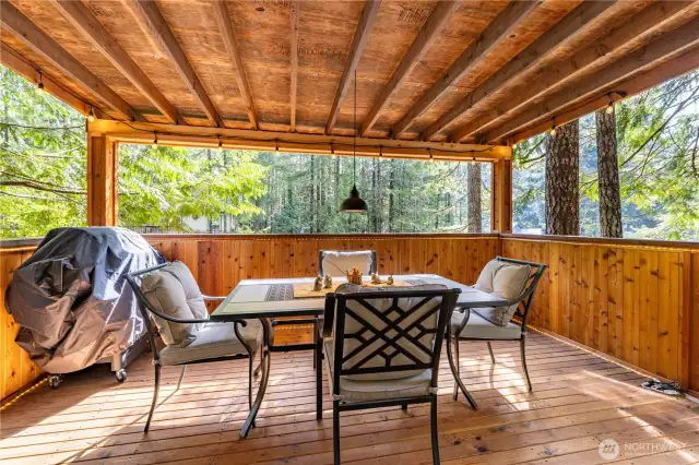 This inviting covered deck is a perfect all-weather retreat, surrounded by trees. With space for outdoor dining