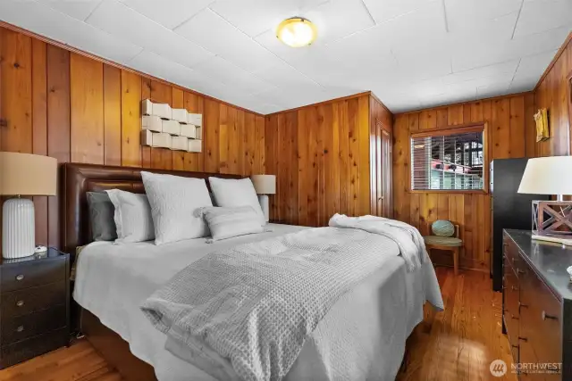 A primary bedroom will have you feeling like you are at a retreat with wood paneled walls and a stunning view of the outdoors.