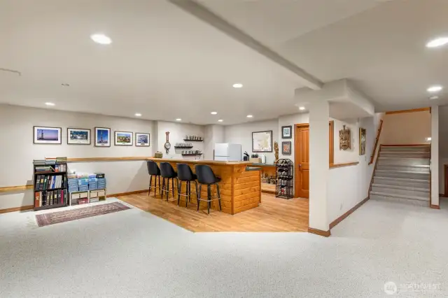 lower level Wet bar and recreation area. The refrigerator conveys. Door to the right of bar is to large storage room.