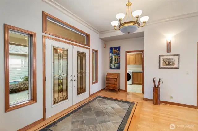 Interior view of the spacious main entry foyer with a slate inlay "welcome area" surrounded with a stylish hardwood floor design. The Laundry Room is conveniently located on the Main Level.
